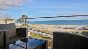 Een balkon met rieten meubilair met uitzicht op een strand en de oceaan.