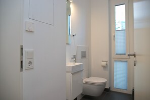 A small, modern bathroom with a toilet, sink, and window. - Seeblick Seaside 16 Inkl. Wlan (Grömitz)