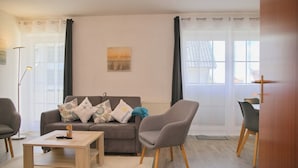 Una sala de estar con sofá, sillones, una mesita de centro y un comedor con mesa y sillas.