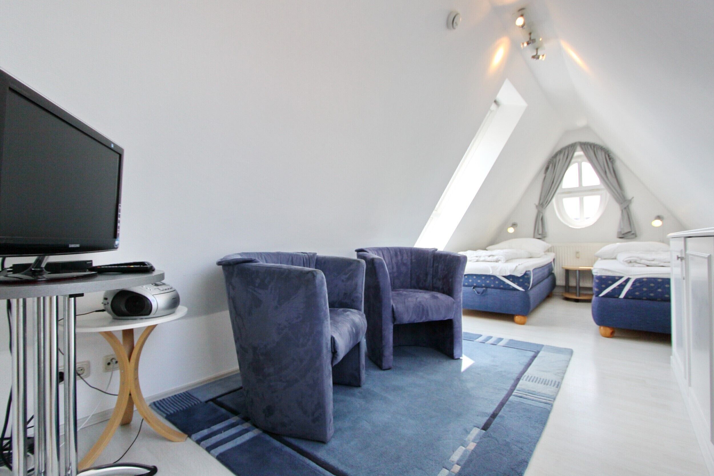 Une chambre moderne équipée d’une télévision, de deux canapés, d’un lit et d’une petite table.