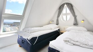 A bedroom with two beds, a window, and a view of the outside.