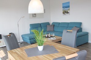 Una sala de estar moderna con un sofá azul, una mesa de centro de madera con una planta y una lámpara.
