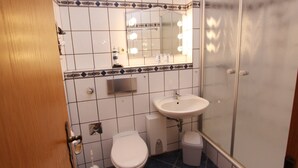 Un bagno con un WC bianco, un lavandino e uno specchio illuminato.