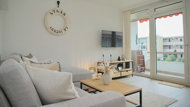 Una sala de estar moderna con un sofá, una mesa de centro y un televisor montado en la pared.