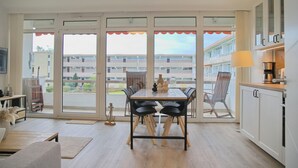 Una cocina moderna con comedor, ventanas amplias y vista a un edificio.