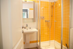 Bathroom features a glass-enclosed shower and a white sink with a mirror.