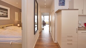 A hotel room with a bed, a wardrobe, a desk, and a view of the living area. - Miramar App. 707 Inkl. Wlan (Grömitz)