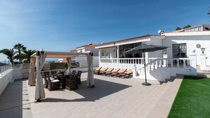 A rooftop terrace with outdoor seating, a pergola, and a white building with a red-tiled roof. - Villa Melua (Chayofa)
