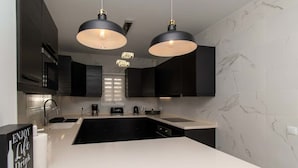 A modern kitchen with dark cabinetry, a white countertop, and pendant lighting. - Villa Melua (Chayofa)