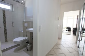 Uma casa de banho moderna com sanita, lavatório e chuveiro.