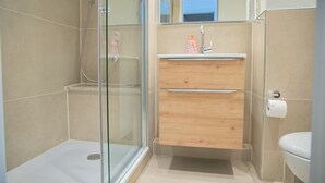 A modern bathroom with a glass shower enclosure, a wooden vanity with a sink, and a toilet. - Miramar App. 705 Inkl. Wlan (Grömitz)