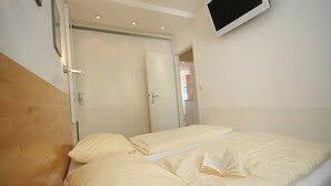 A bedroom with two beds, wooden headboards, and a mounted TV. - Miramar App. 705 Inkl. Wlan (Grömitz)