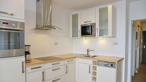 A modern kitchen with white cabinets, stainless steel appliances, and a wooden countertop. - Miramar App. 705 Inkl. Wlan (Grömitz)