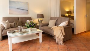 A living room with two sofas, a glass coffee table, and a painting of a beach. - Miramar App. 503 Inkl. Wlan (Grömitz)