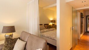 A hotel room with a bed, a sofa, a lamp, and a glass door leading to a hallway. - Miramar App. 503 Inkl. Wlan (Grömitz)