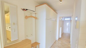 Una habitación de hotel con tocador de madera, espejo, armario y suelo de baldosas.
