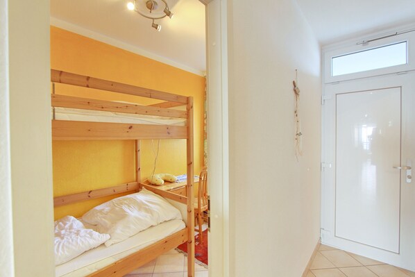 A room with a bunk bed, a desk with a chair, a wardrobe, and a window. - Grömitz-center II App. 34 Inkl. Wlan (Grömitz)