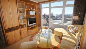 Un salon avec un téléviseur, un canapé et une table basse en verre.