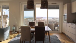 A modern kitchen with a large sliding glass door leading to a balcony with a city view.