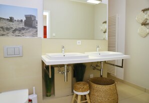A bathroom with two sinks, a mirror, a towel rack, and a trash bin. - Seeblick Seeloft Inkl. Wlan (Grömitz)