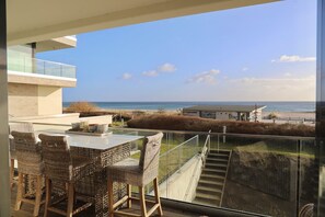 A balcony with wicker furniture overlooking a beach and ocean. - Seeblick Seeloft Inkl. Wlan (Grömitz)