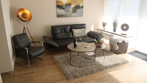 En moderne stue med sofa, lænestol, sofabord og gulvlampe.