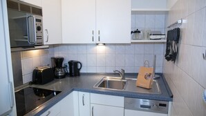 A compact kitchen with white cabinets, a built-in microwave, a coffee maker, a toaster, and a Siemens dishwasher. - Hanseat I Appartement. 79 (Grömitz)