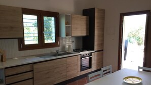 Une cuisine moderne avec des meubles en bois, un plan de travail blanc, une cuisinière et un évier.