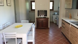 Une cuisine de taille réduite avec un coin repas, un téléviseur et un sol carrelé.