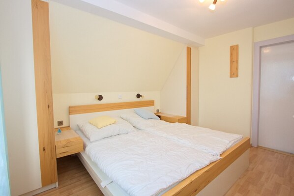 A bedroom with a single bed, a nightstand, a wooden headboard, and a door.