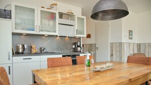 Eine moderne Küche mit weißen Schränken, einem Holzespeisetisch und orangefarbenen Stühlen.