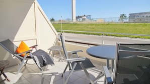 En balkon med en stol, et bord og udsigt til en høj bygning.