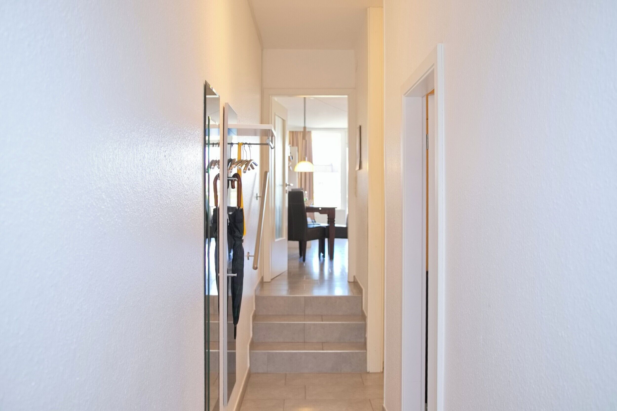 A hallway with a staircase leading to a dining area.
