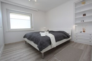 Une chambre à coucher comprenant un lit, une fenêtre, une table de chevet et une étagère intégrée.