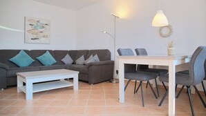 A modern living room with a sofa, a dining table, and chairs. - Haus Belvedere App. 26 Wlan Inkl (Grömitz)