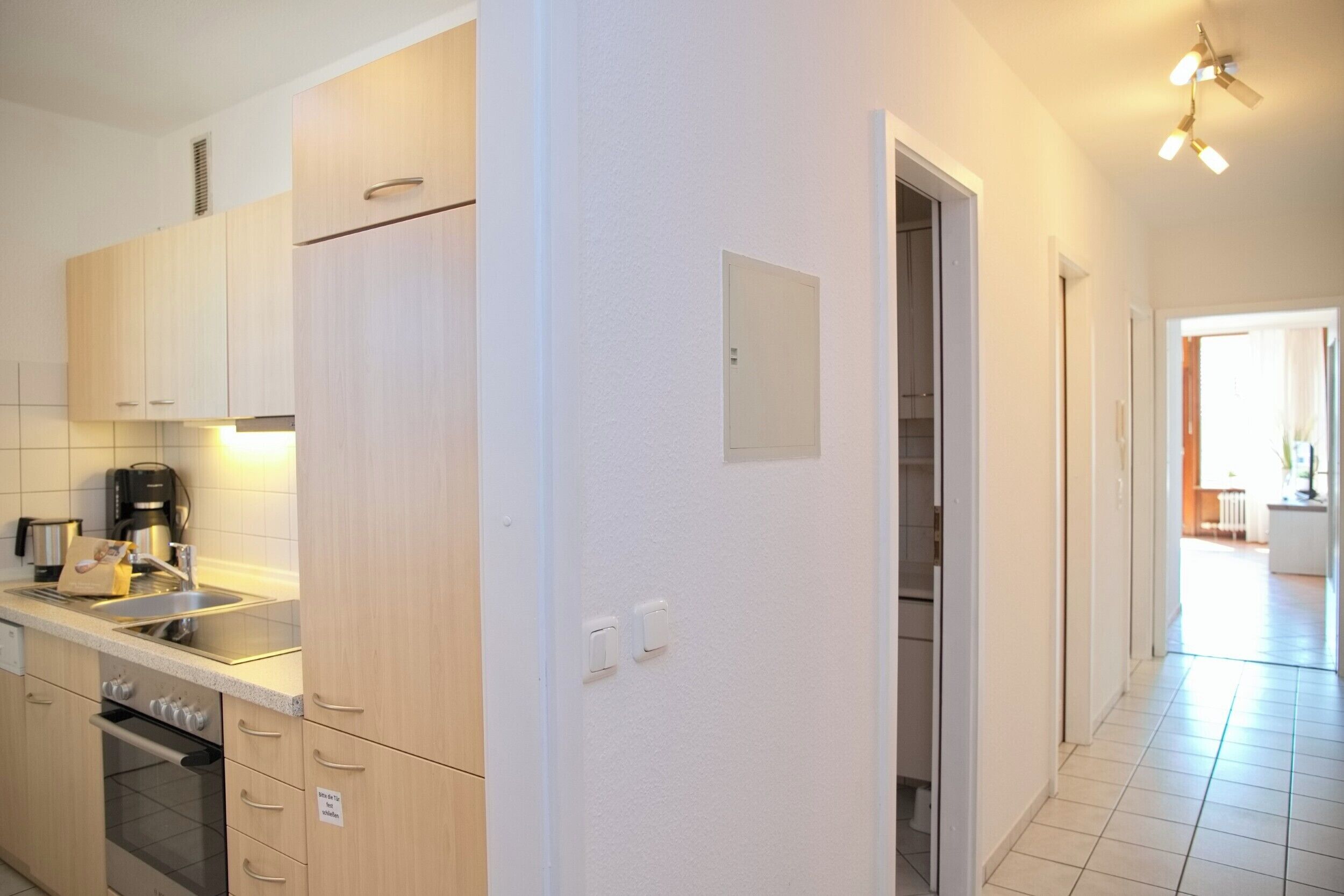 A modern kitchen with wooden cabinets, a built-in oven, and a stainless steel sink.