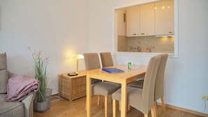 A dining area with a table, chairs, a lamp, a potted plant, and a view of the kitchen. - Haus Belvedere App. 28 Inkl. Wlan (Grömitz)