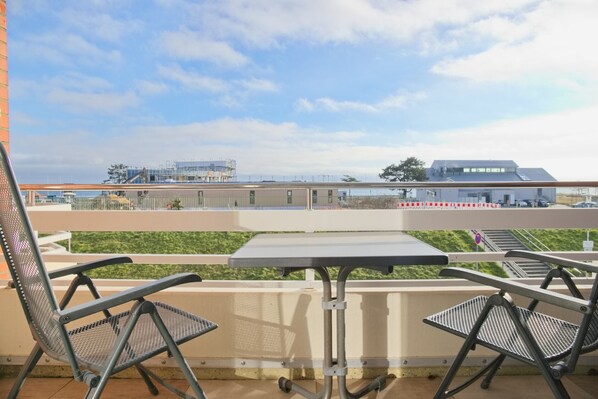 Enjoy a peaceful moment on the balcony with a table and two chairs overlooking the building's sleek design.