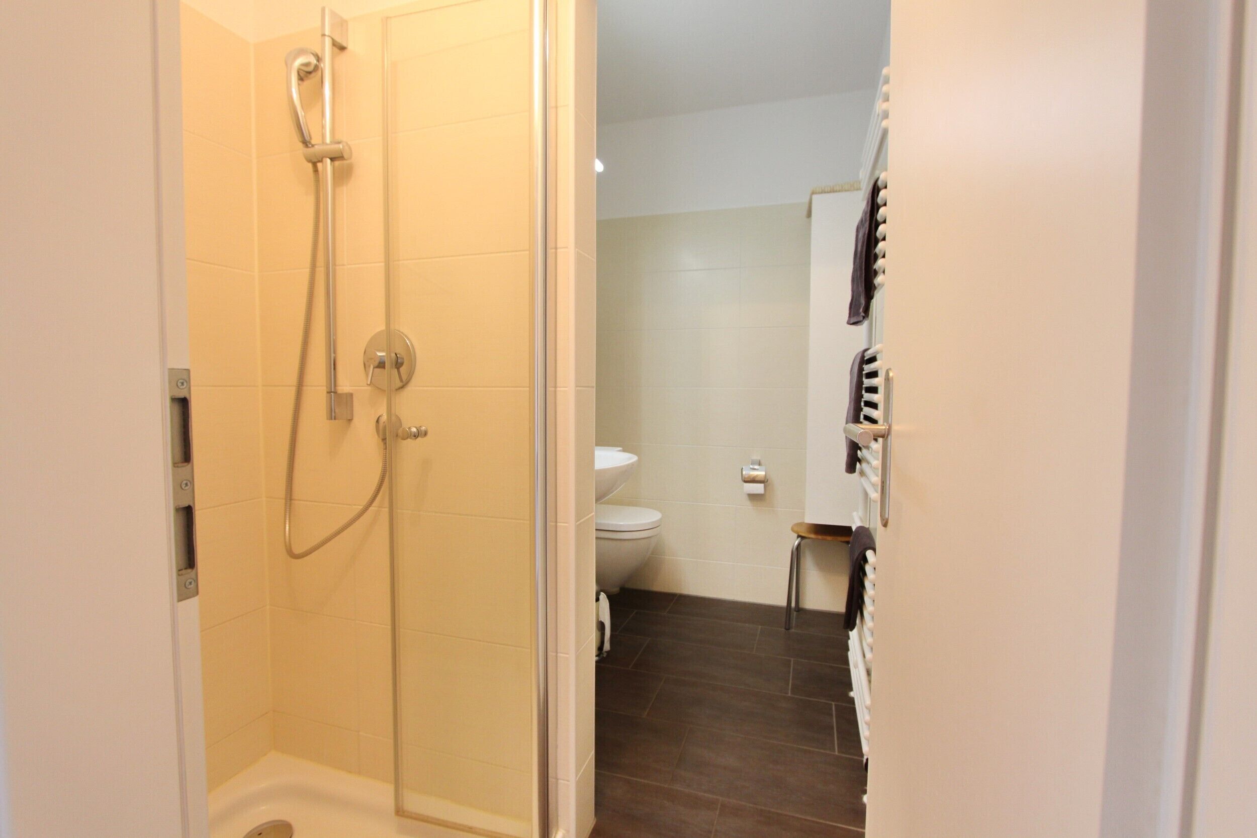 Een badkamer met een douche, toilet en een handdoekhouder.