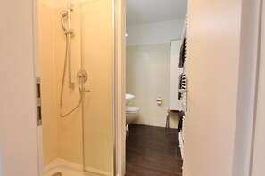 Une salle de bain avec une douche, des toilettes et un porte-serviettes.