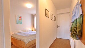 A bedroom with a bed, a nightstand, and a wall-mounted shelf. - Haus Belvedere App. 45 Wlan Inkl (Grömitz)