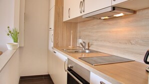 A modern kitchen with white cabinets, a wooden countertop, a stainless steel sink, and a built-in oven. - Haus Belvedere App. 45 Wlan Inkl (Grömitz)