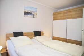 Ein Doppelbett mit Holzvorhang, zwei Nachttische mit Lampen und ein gro ßer Kleiderschrank mit Spiegel.