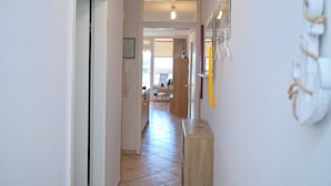 Un pasillo con un banco de madera, una puerta y una lámpara fijada a la pared.