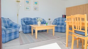 A living room with two blue checkered sofas, a wooden coffee table, a vase with flowers, and a wooden chair. - Haus Belvedere App. 64 (Grömitz)