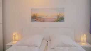 A bedroom with a bed, white pillows, and two bedside lamps. - Haus Belvedere App. 64 (Grömitz)