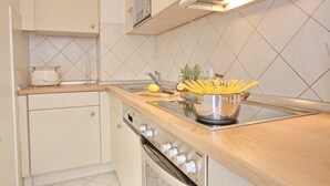 Une cuisine avec des armoires blanches, une cuisinière en acier inoxydable et un dosseret carrelé.