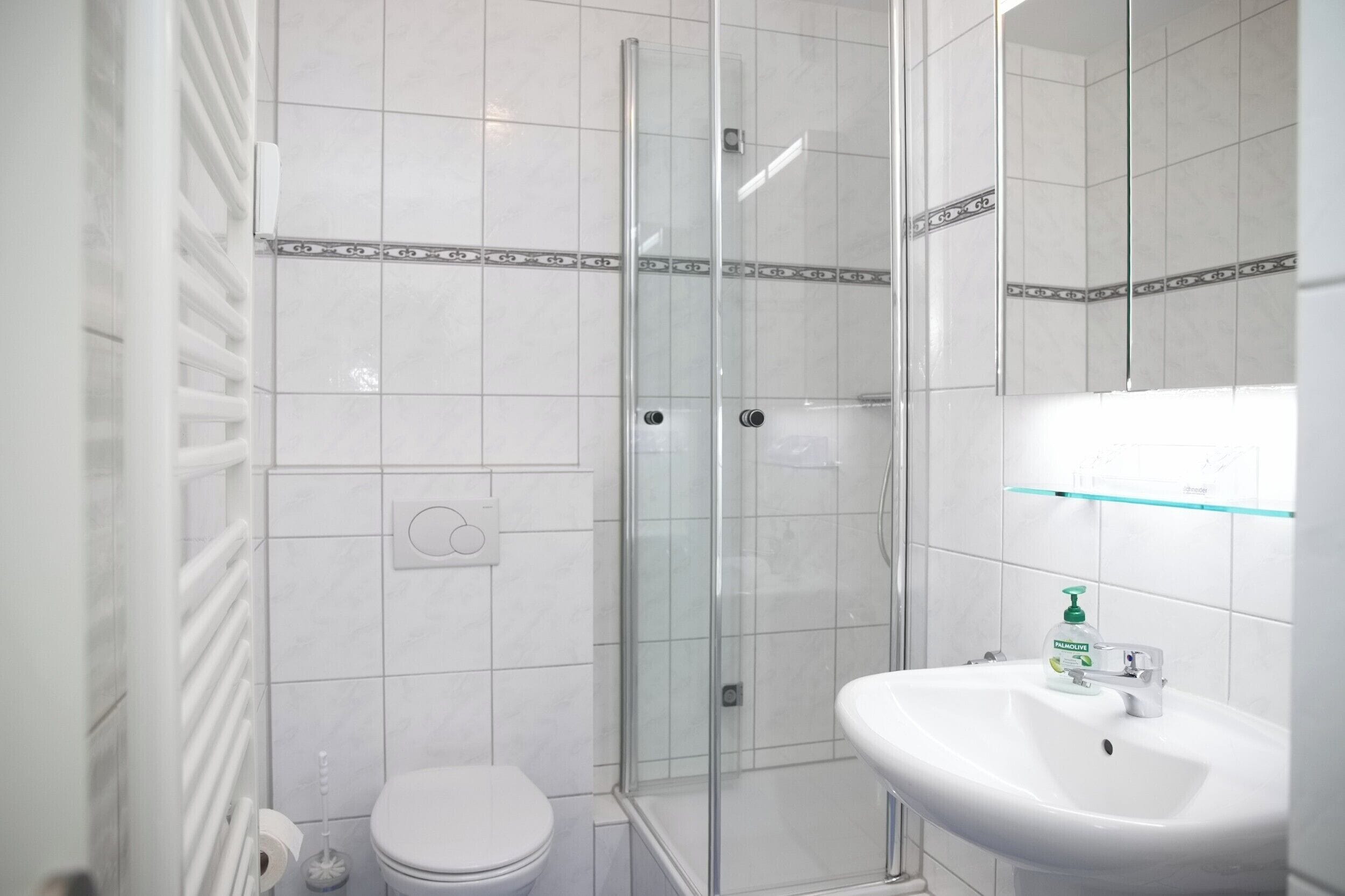 A bathroom with a glass shower enclosure, a white sink, and a toilet.