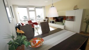 A modern dining area with a long table, chairs, and a potted plant. - Haus Belvedere App. 75 Wlan Inkl (Grömitz)