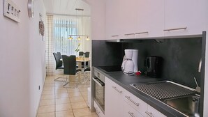 Une cuisine moderne avec des meubles blancs, un plan de travail noir et une machine à café.